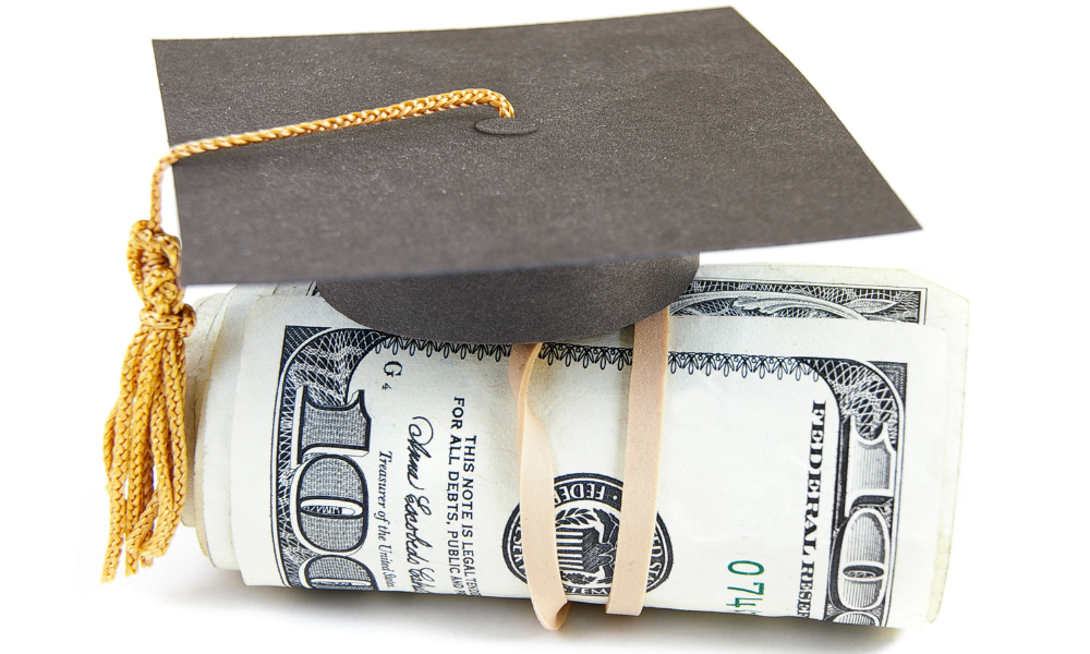 Graduation hat on top of a wad of money for college