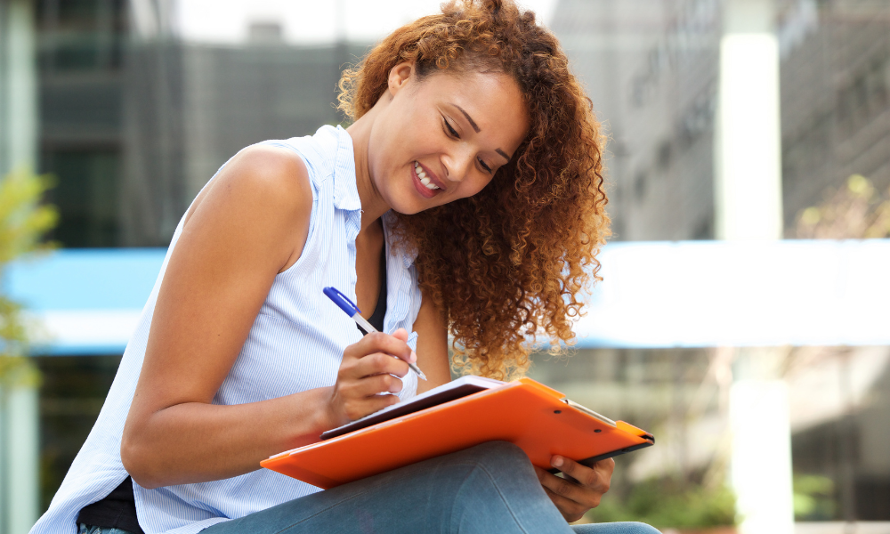 Minority student sitting outside applying for college scholarships, Hispanic scholarships, Latino scholarships, People of color, minorities, HACU, academic merit, financial assistance, Spring Scholarships to Apply for Over Spring Break