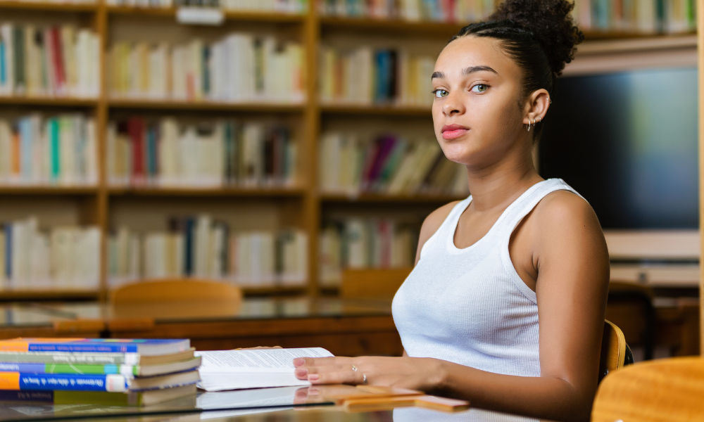 Female grad student in the library looking for scholarships for her masters program, grad student scholarships due in April