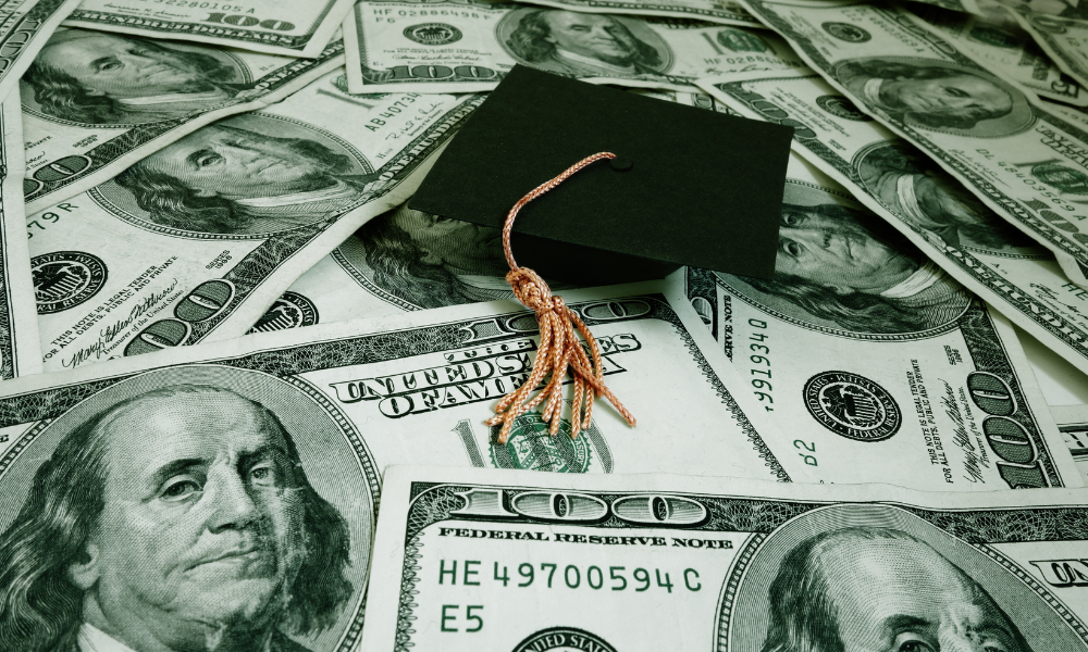 A high school graduation cap on top of a pile of scholarship money, first year of college, underrepresented minority students, two-year scholarship, scholarship's mission, essay scholarship, easy scholarship, financial assistance, senior year, scholarship funds, historically black colleges, HBCUs, HCAUs, black students