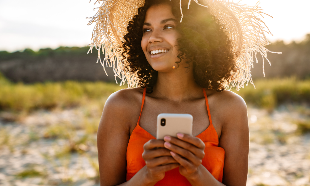 College female enjoying the summer weather while applying for Scholarships for Black Students in June on her cell phone, eligible students, minimum gpa, criteria, college scholarships, federal student aid, high school students, graduate students, incoming freshmen, leadership skills, letters of recommendation