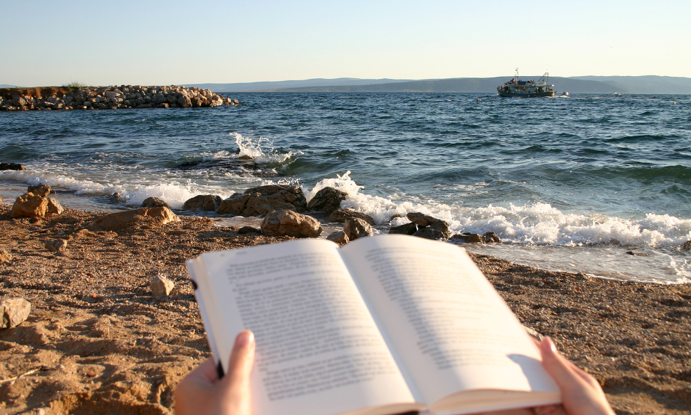 A student at the beach reading a book and applying for scholarships with summer deadlines, July scholarships, leadership skills, marine science, scholarship committee, award amount, community service, july scholarships, financial support, free application, essay scholarship, short essay, graduate school