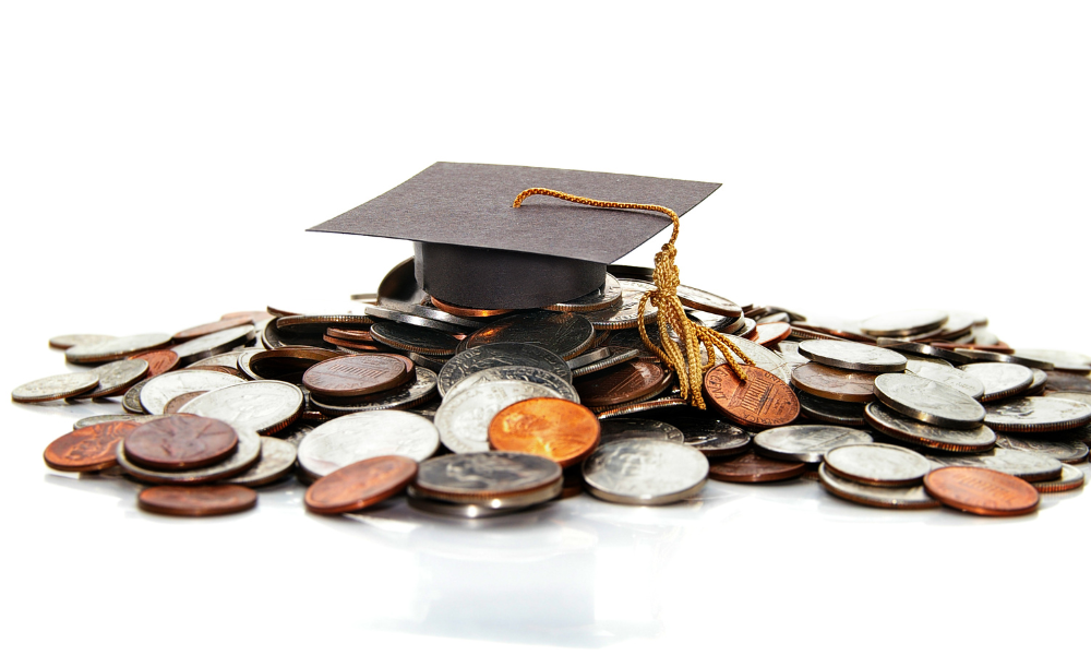 A graduation cap on top of a pile of coins. The student has won money from applying to easy scholarships with no essays. The student has a list of October scholarships with upcoming deadlines