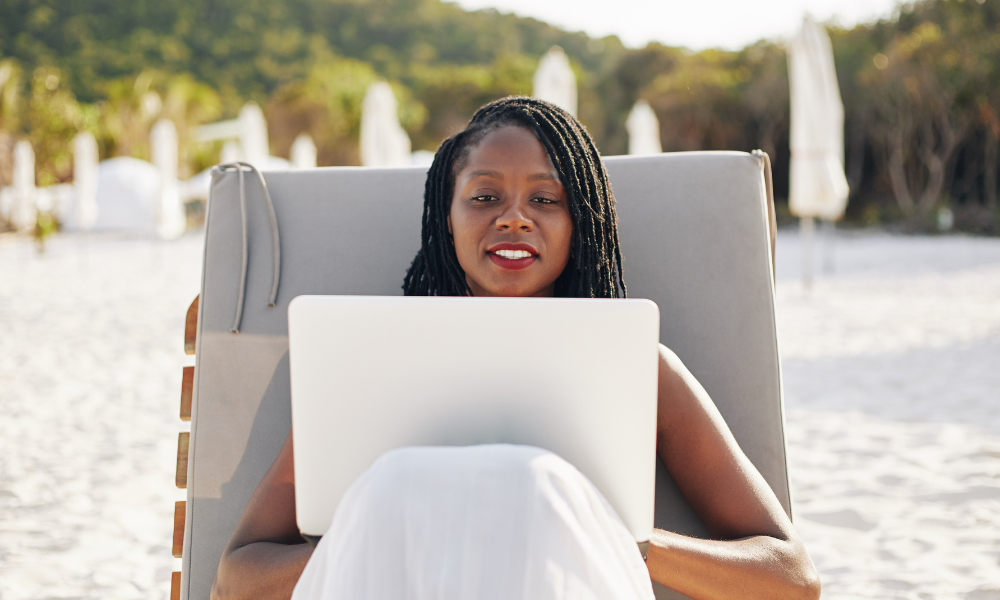 A student is sitting on the beach applying for end of summer scholarships for high school seniors on her lap top