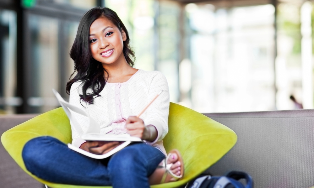 A college senior is in her campus library making a list of law programs, the application process, and law scholarships with upcoming deadlines.