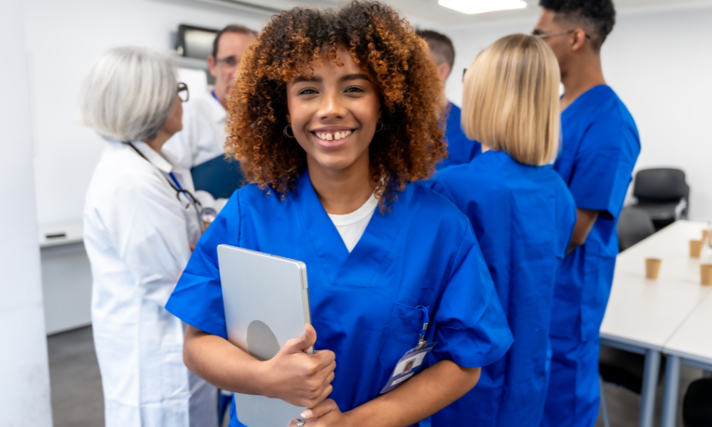 High school senior is dressed in her scrubs and is shadowing nurses for her CNA program. She also is using her tablet to locate nursing scholarships for incoming freshmen. She has already applied to Nursing scholarships with summer deadlines.