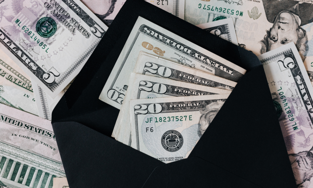 An HBCU student is counting a stack of twenty dollar bills to make sure she has enough money to pay for her college expenses. The student is also reviewing a list of June scholarships for minority students