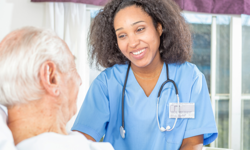 A female nursing student is assisting a patient while being observed by her clinical director