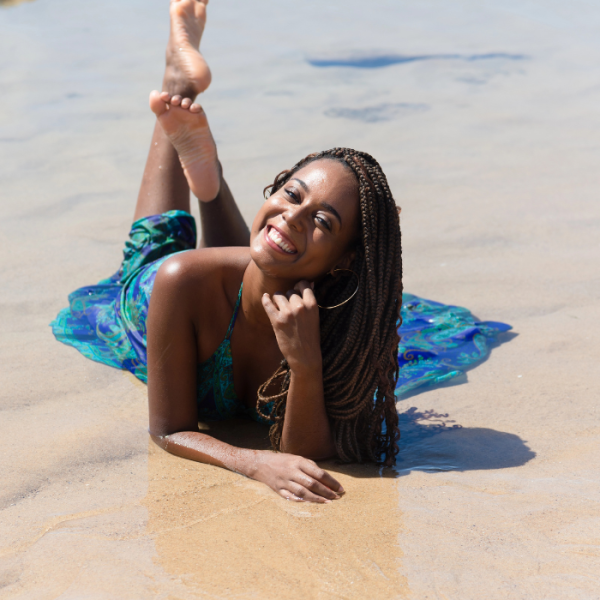 A female college student is relaxing on the beach after applying for several late summer scholarships for college freshmen, college sophomores, college juniors, and college seniors.
