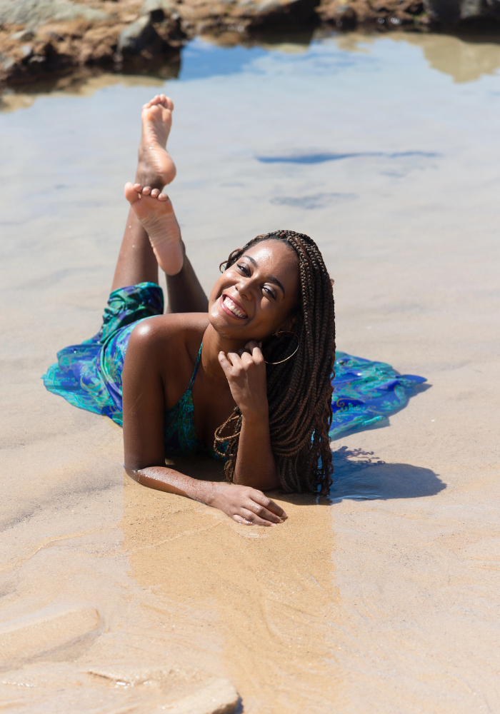 A female college student is relaxing on the beach after applying for several late summer scholarships for college freshmen, college sophomores, college juniors, and college seniors.